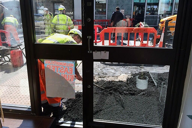 Workmen digging directly outside the door of 25 Ten Boutique