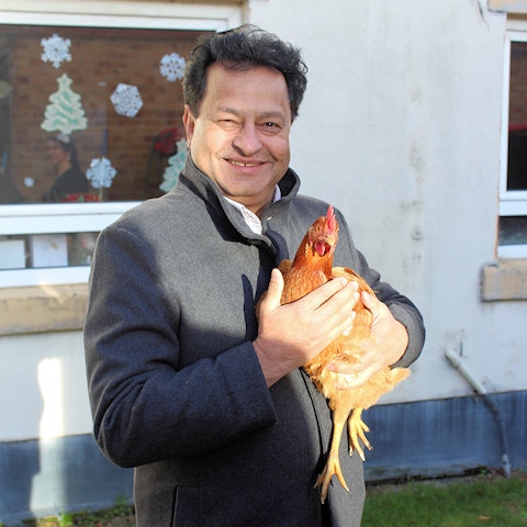 Councillor Iftikhar Ahmed, cabinet member for adult care, with one of the hens at Cleggsworth House Care Home 