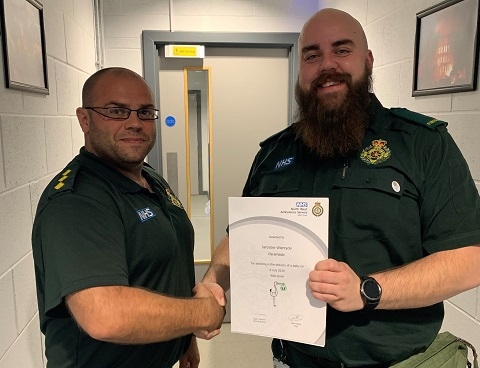 Paramedic, Jaroslaw Wierzycki is presented with a certificate and NWAS baby pin badge