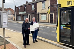 Kevin and Sarah holding up signs as a bus pulls in next to the cycle lane in Castleton