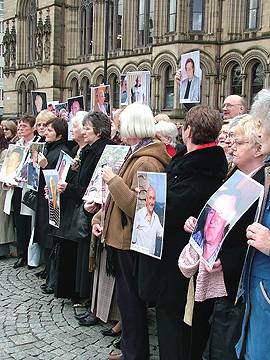 Widows hold up photos of loved ones