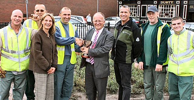 Chief Executive Roger Ellis and Councillor Wera Hobhouse present Middleton’s street services team with the Chief Executive Landscape Award trophy at the winning site opposite the Dusty Miller pub.