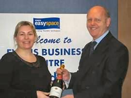 Kirsty Gorrill receiving a bottle of champagne from Managing Director, Tom Stokes.