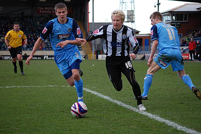 David Perkins skips past two Grimsby defenders