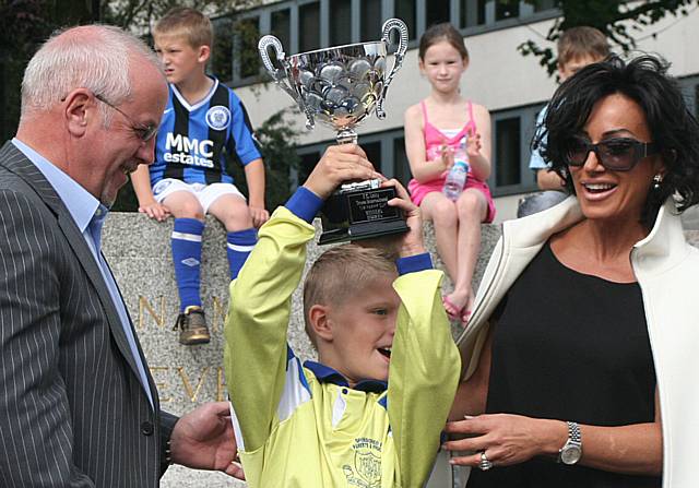 Colin Parry and Nancy Dell'Olio present the cup to Milnrow Parish under-11s' captain.