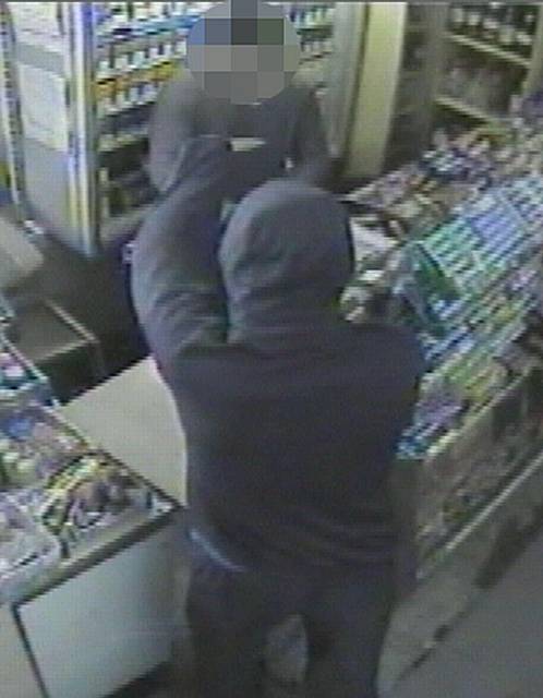 The armed robber threatens the shopkeeper at the Heywood newsagent with a knife before making off with cash.