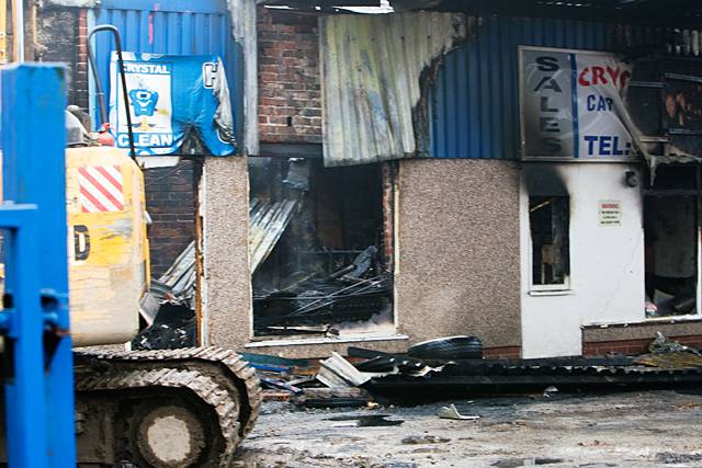 A digger clears debris at the devastated car wash.