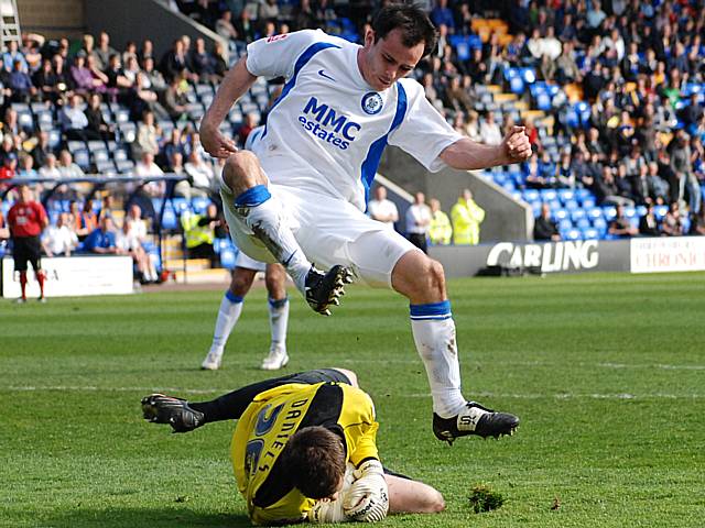 Chris Dagnall hurdles Shrewsbury keeper Luke Daniels as he gathers the ball.