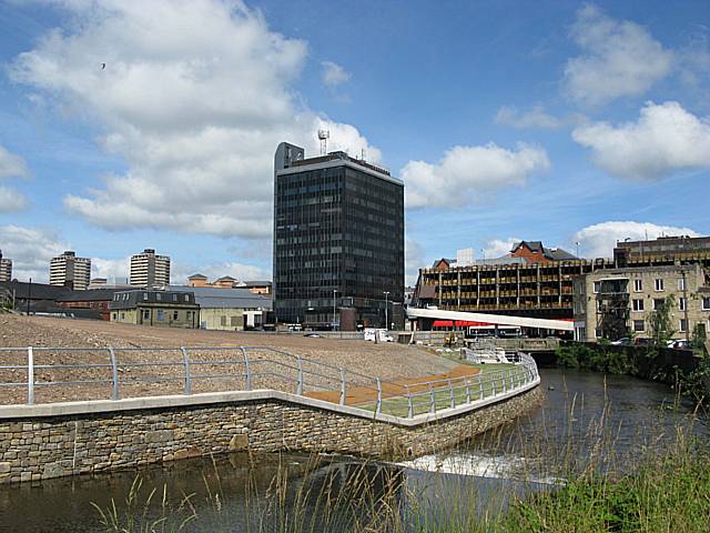 A riverside site has been cleared for the new transport interchange and a new river bank wall has been built. The demolition of the Council offices and bus station shown in the background and relocation to the riverside site will clear space for the £200 million redevelopment.