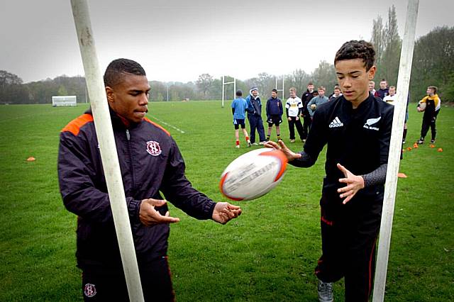 Kyle Eastmond shows camp participant Isaac Noi some techniques.