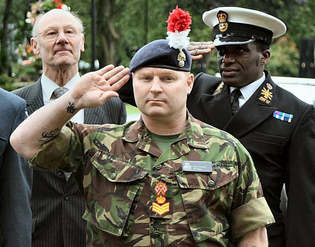 Members of the armed forces salute as the flag is raised.