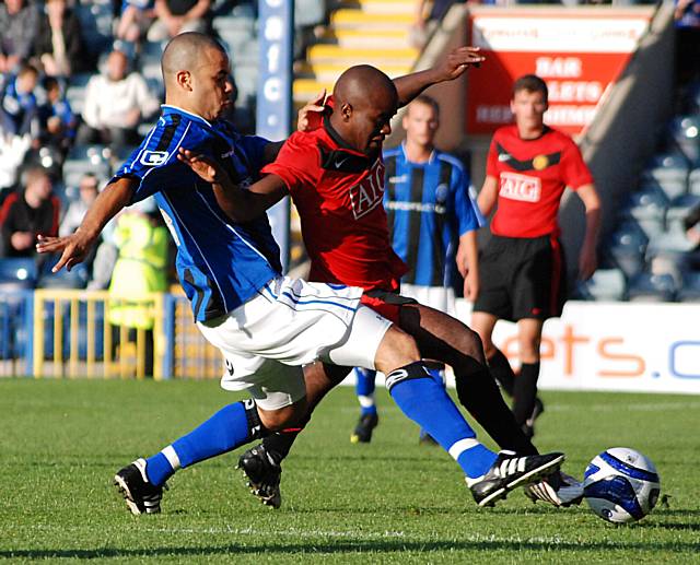 Marlon Broomes slides in on Fabian Brandy.