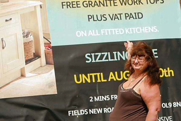 Trisha Boileau, landlady from the Waggon and Horses pub pointing at the large billboard blocking the view to her pub for over a year

