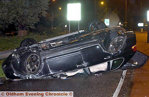 The Porsche Cayenne on its roof at the site of the crash.