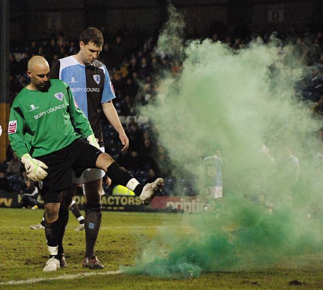 Brown kicks a flare, thrown by someone in the Rochdale end, off the pitch.