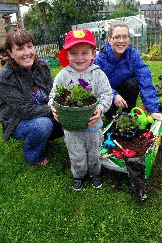 Meggie Heap, Community Project Manager, Seddon, Ayden Heap, 3, Mhorag Saxon, Project Officer, Groundwork Oldham & Rochdale, planting donated violas with new tools 
