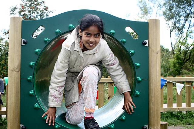 Young girl climbs through a tunnel