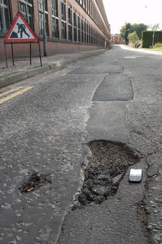 The potholes which have not been repaired. The mobile phone next to the hole is to highlight its size