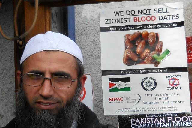 A staff member at Haji Cash and Carry with their MPACUK poster