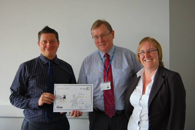 Jonathan Mayes receives his award from Chairman John Pierce, along with nominator Karen Kenton 
