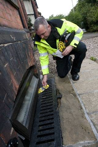 Inspector Steve Clarke posting a footprint leaflet through an open window