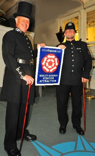 Volunteers Tom Hughes and Ron Flowers showing off the Quality Assured Visitor Attraction (QAVA) status sign. 

