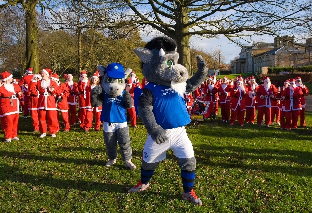 Rochdale AFC club mascots Desmond the Dragon and Desmond’s son Dale warm-up the Santas