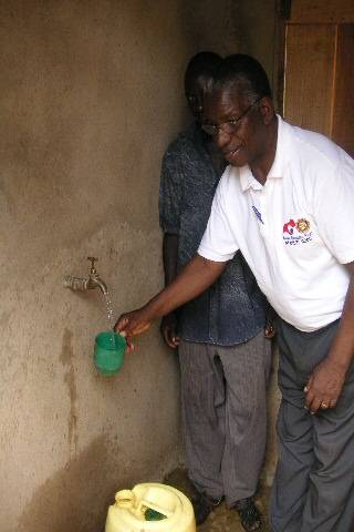 The kiosk where the women collect the clean rain water with the President of the Rotary Club of Meru collecting some water 