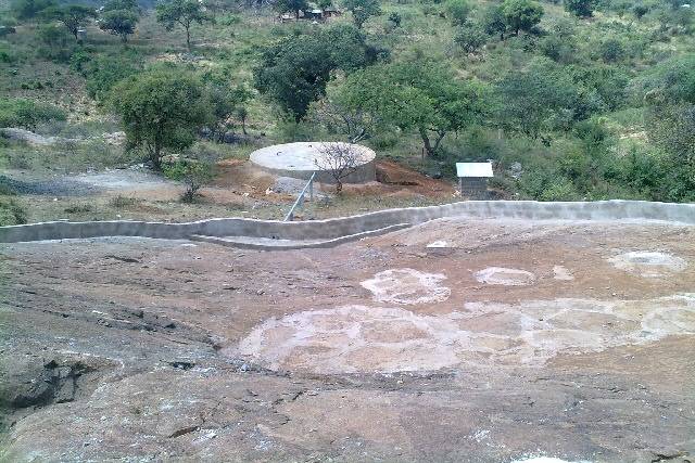 The pipe from the wall to the top of the tank and the kiosk where the community collect the water. 