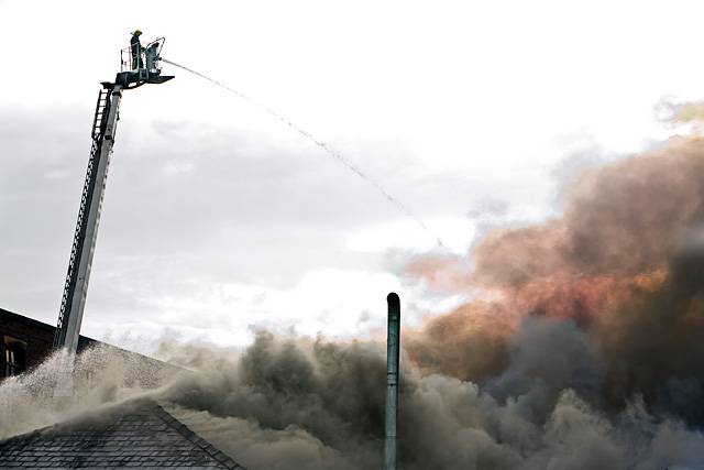 Fire fighter tackles the blaze at Sartex Quilts and Textiles from the high platform