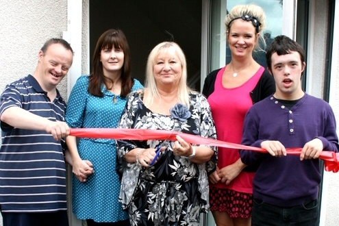 Councillor Robinson cuts the ribbon to the doors of the new centre, with service users and managers of the centre