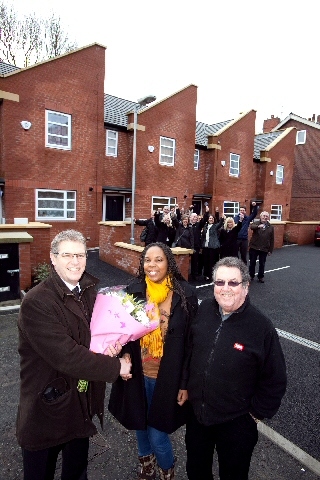 Hill Street resident Miss Marjorie Mutemasango is presented with flowers by Guinness Northern Counties’ Director of Neighbourhood Services John Cockerham (left) and Councillor Peter Rush.
