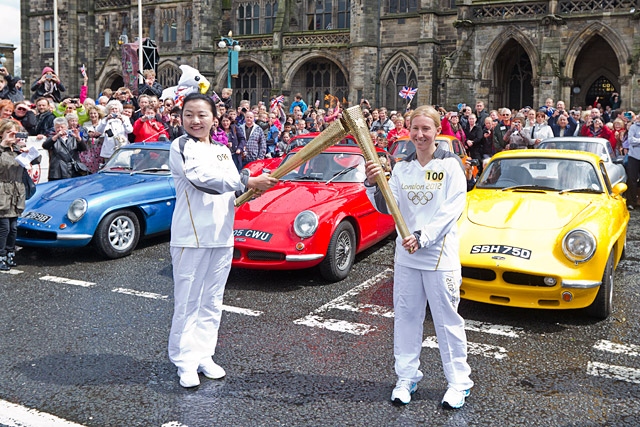 Wensheng Li and Amy Peckover at the Olympic Flame hand over in Rochdale Town Centre, with the 'Rochdale Olympic Cars' in the background