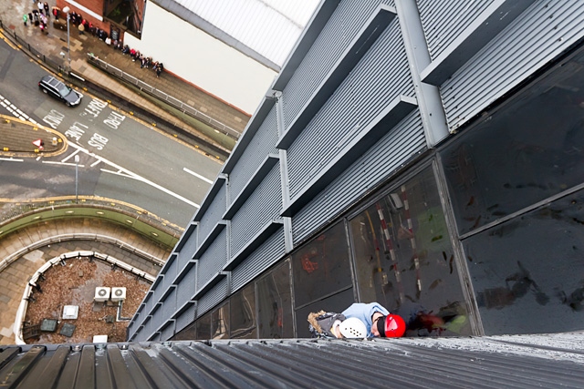 Adam Kutereba abseiling down the 230 foot black box encouraged by Mark Bland