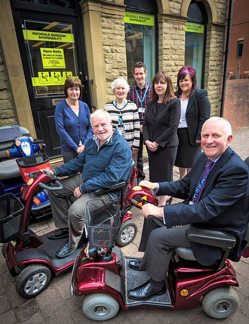 Outside Shopmobility’s new premises in Rochdale town centre are front (left-right) Councillor Allen Brett, Shopmobility Trustee and Councillor Ashley Dearnley, Shopmobility Chairperson. Back (left-right) are Scheme Assistant Michelle Davies; Councillor Janet Darnbrough, Shopmobility Trustee; Jonathan Hindle, Senior Project Manager at Rochdale Development Agency;  Michelle Hollinrake, Shopmobility Manager and Debbie O’Brien, Shopmobility Treasurer