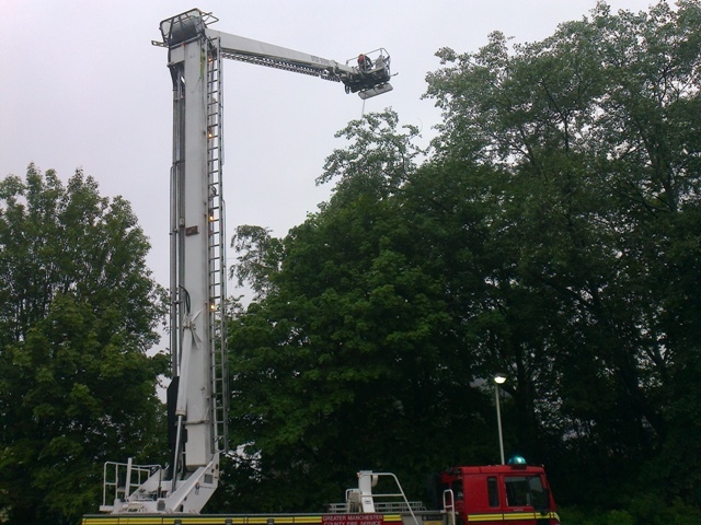 Fire-fighters wearing masks and using a fully extended ladder to fight the blaze