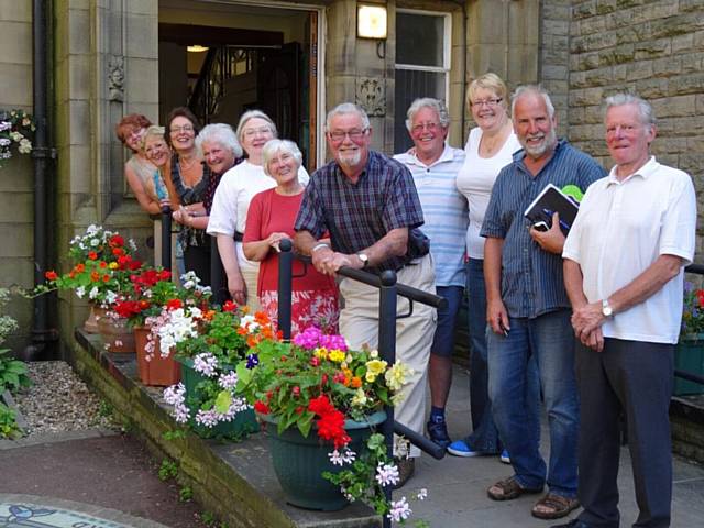 The Pennines in Bloom team outside Milnrow Library – complete with flowering pots, hangers, etc