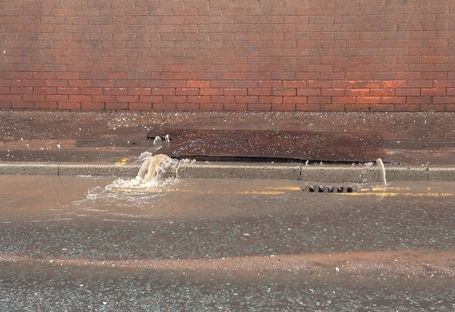 Water streams onto Queensway