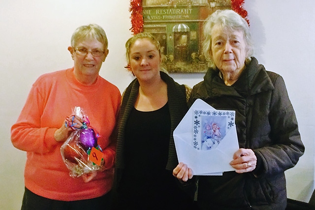 Customers Kay and Barbara receiving raffle prizes from cafe worker Rachel Clegg