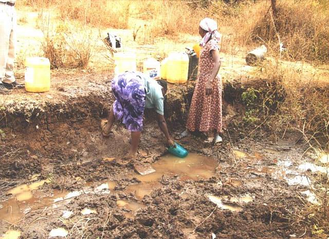 2 women trying to get 20 litres of dirty water from a ditch. This photo was taken before the first project started. They had walked for over 4 hours from their home to find this water