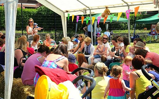 Parents and children gather round for story-time in the park