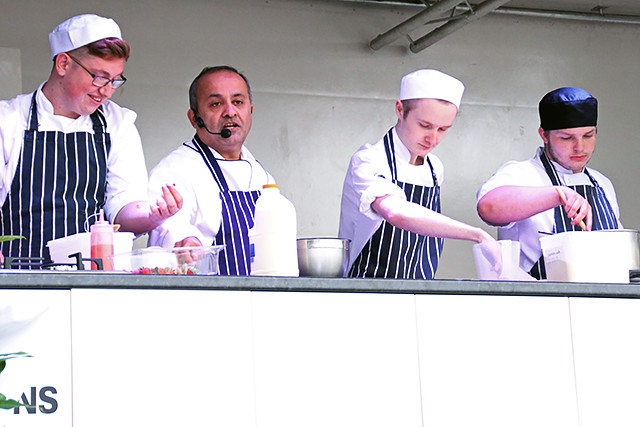 Aazam Ahmad with Hopwood Hall students Damien Thompson, Tom Basford and Adam Duxbury cooking on stage at The Feel Good Festival