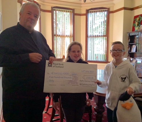 Kats dancer Eve Iddon and Kyle Briggs Williams present Father Paul Daly with a £500 cheque for the Heywood foodbank. 