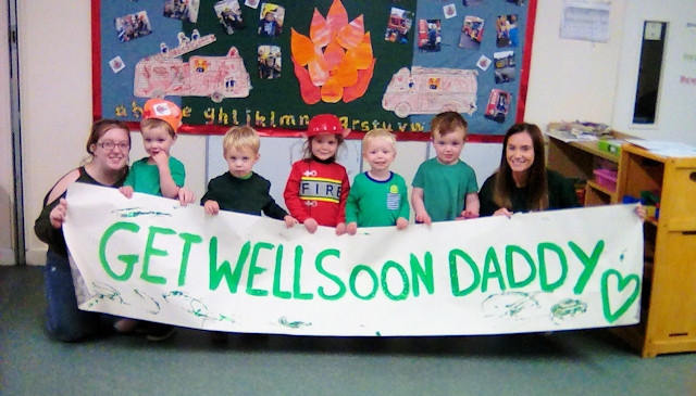 Zach and his keyperson Beth (both far right) hold the sign Zach and his friends painted for fireman Alex Green