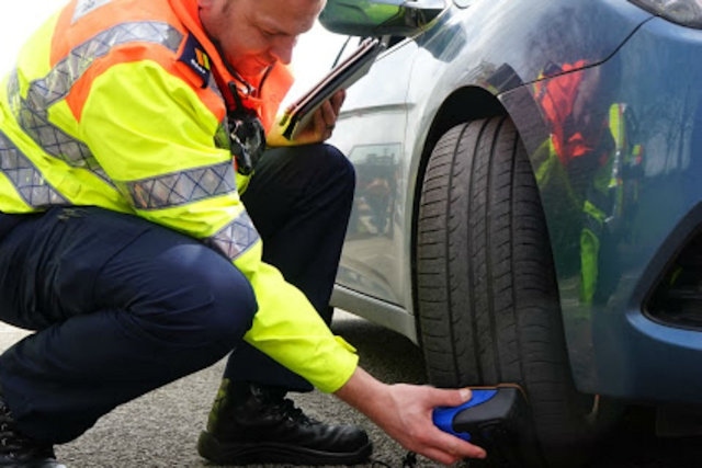 Highways England traffic officer Neil Waring checking car tyres