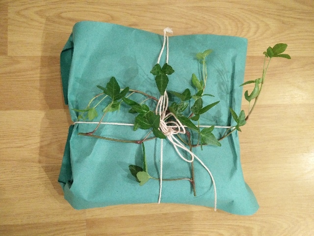 Gifts wrapped in children’s coloured drawing paper tied with natural string and decorated with ivy cut from a house plant