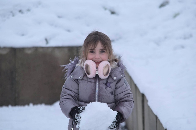 a little girl holds a snowball