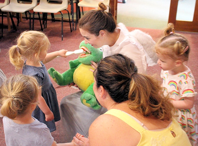 Children clean an alligator's teeth with the help of a tooth fairy