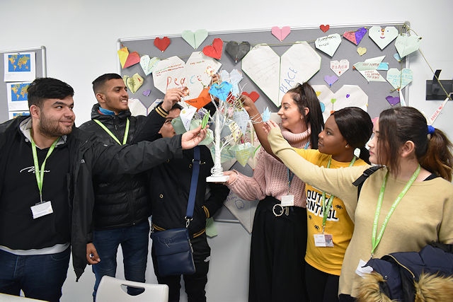 Eloise Dale (centre) and her ESOL students with their origami cranes, peace tree and peace wall