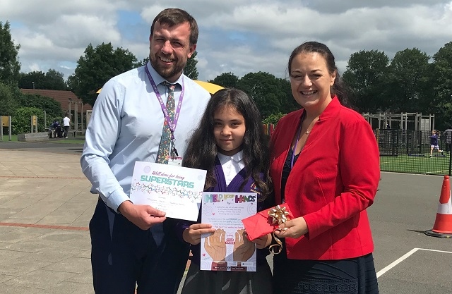 Tabassom being presented with her winning certificate, poster and voucher by staff at Sandbrook Primary 